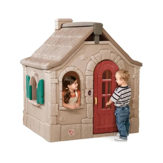 Kids playing with a realistic outdoor cottage playhouse featuring red door, green shutters, and stone design